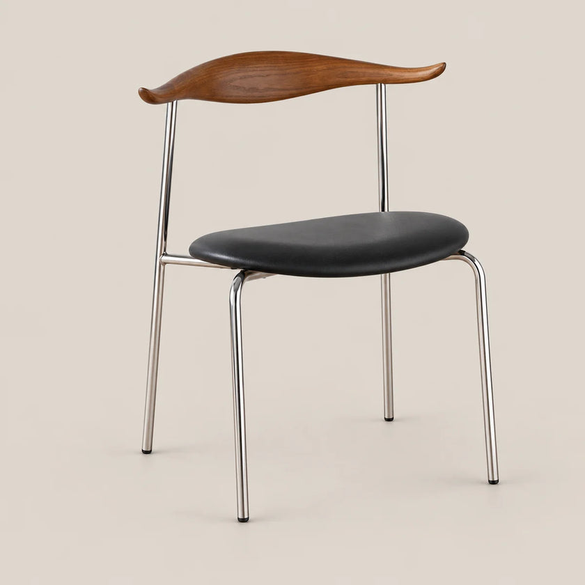 A mid-century modern dining chair featuring a curved wooden backrest, a black upholstered seat, and a chrome metal frame, set against a solid beige background.
