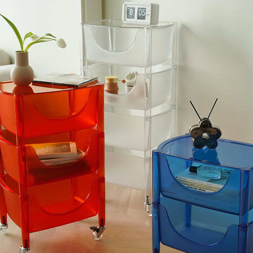 Three transparent storage units in red, clear, and blue with various items on top.