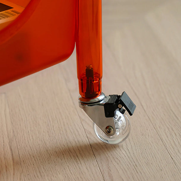 Close-up of a red chair leg with a wheel on a wooden floor