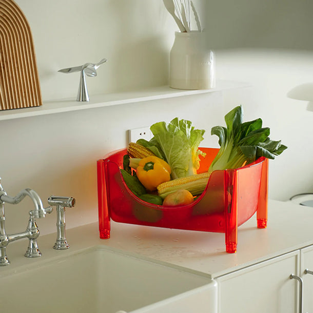 Red vegetable bin with fresh produce on a kitchen counter