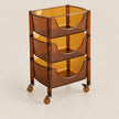 A three-tier rolling storage cart made of translucent amber plastic with black metal hardware and casters, shown on a light beige background.
