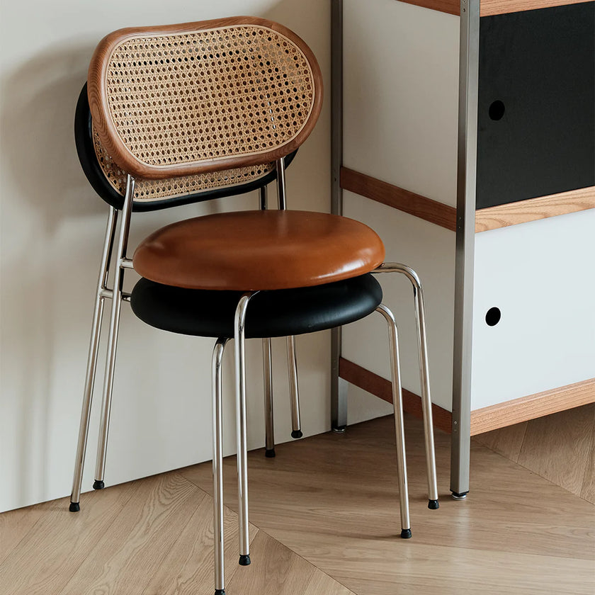 Stackable chair with wicker backrest and leather seat in a room setting.