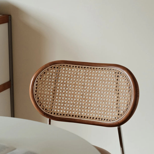 Wicker chair with wooden frame against a neutral wall