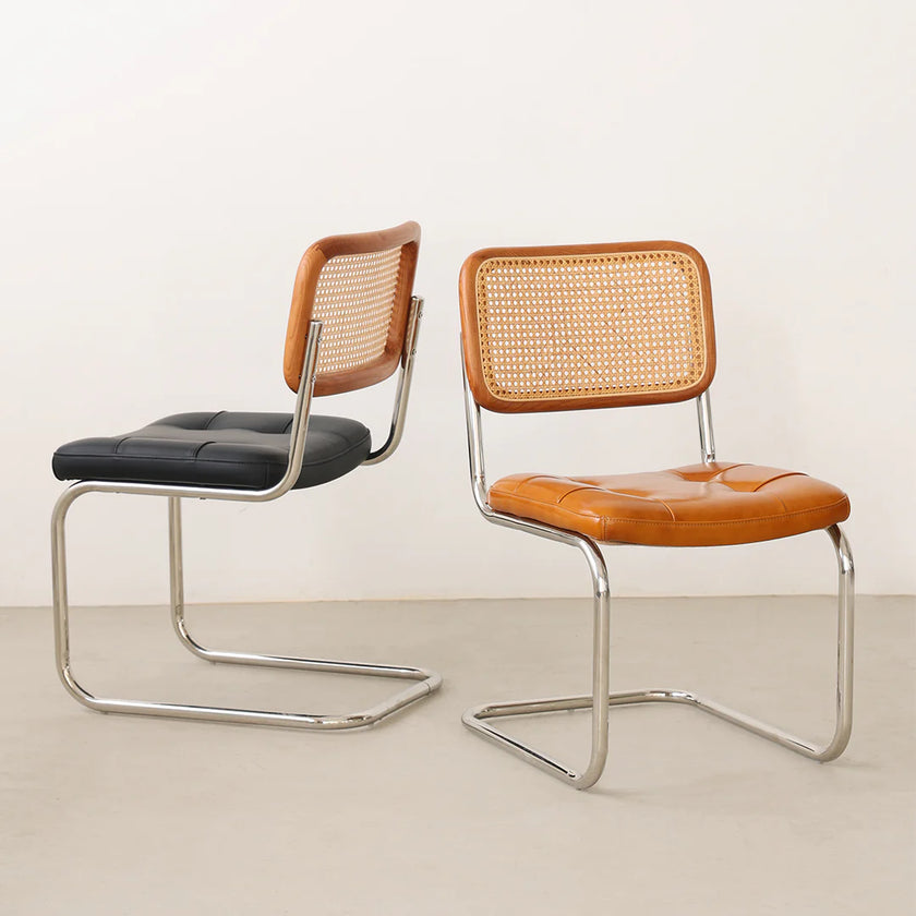 Two chairs with wicker backrests and leather seats on a plain background