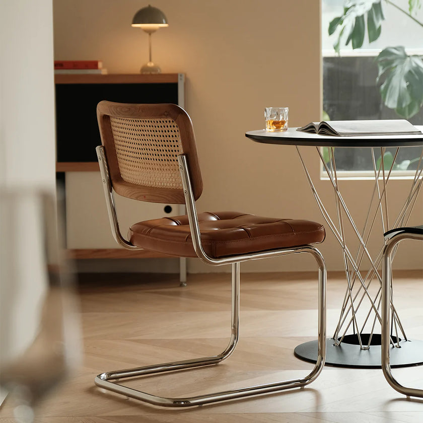 Brown chair with metal frame in a room with a table and lamp.