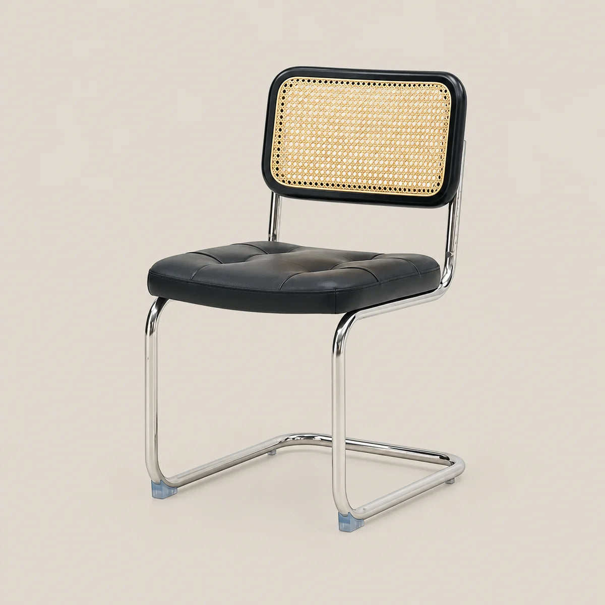 A modern dining chair with a black tufted faux-leather seat, a black-framed cane backrest, and a chrome cantilever steel base, shown against a solid beige background.