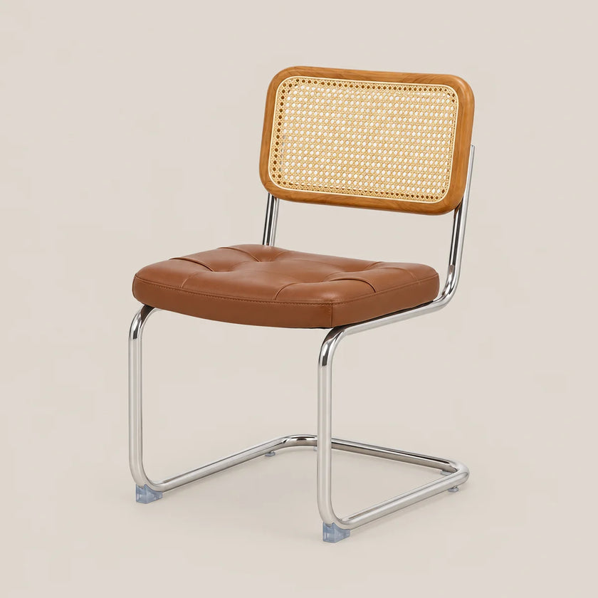 A modern side chair with a brown leather seat and a woven cane backrest, supported by a chrome cantilever frame, set against a solid beige background.