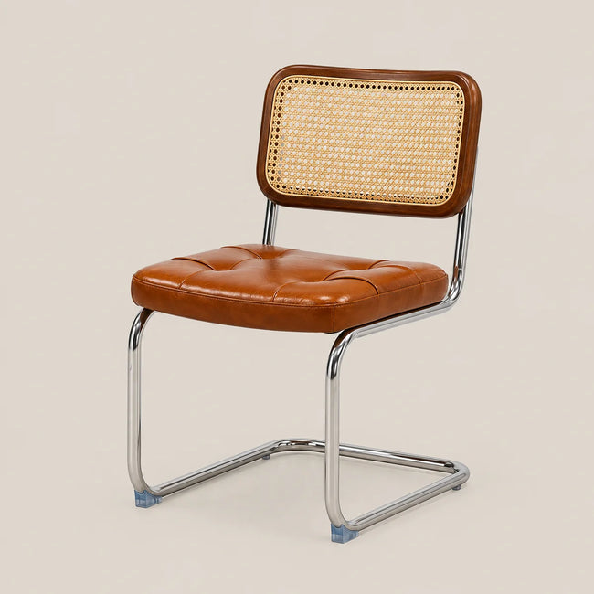 A modern side chair with a tufted cognac brown leather seat and a woven cane backrest, supported by a chrome cantilever frame on a light beige background.