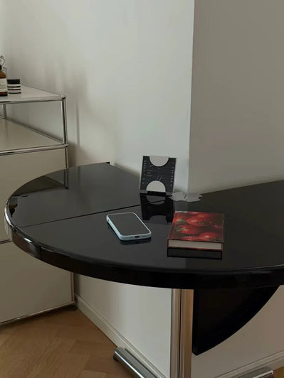 Black round table with a smartphone and book on a white wall background