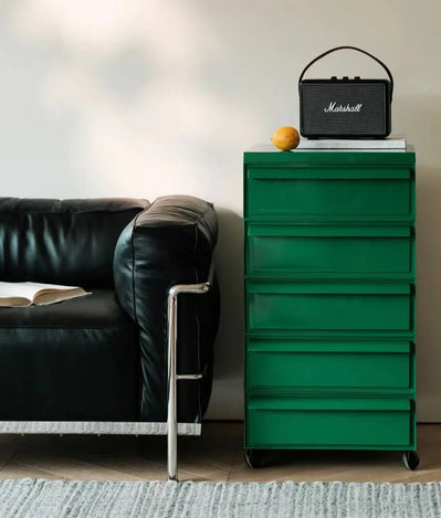 Green dresser with a Marshall speaker on top next to a black leather sofa.