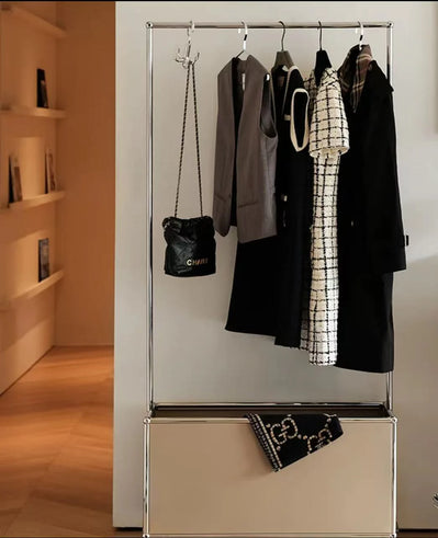 Clothing rack with clothes and bags against a white wall