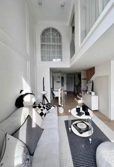 Modern living room with high ceiling, white walls, and a black and white color scheme.
