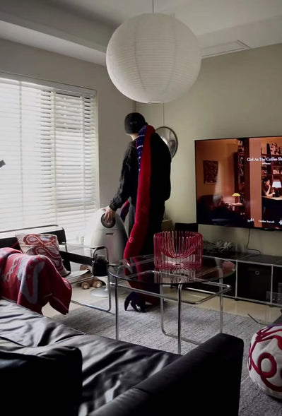 Person standing in a living room with a television on the wall