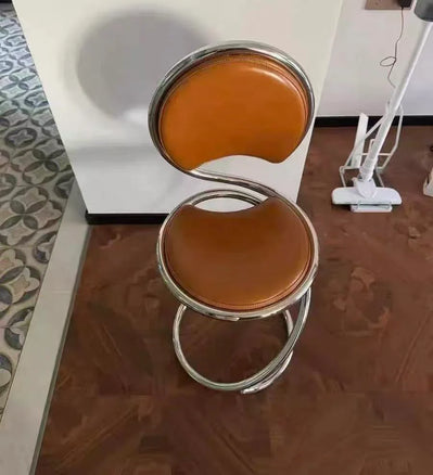 Brown cushioned chair with metal frame on a reflective floor