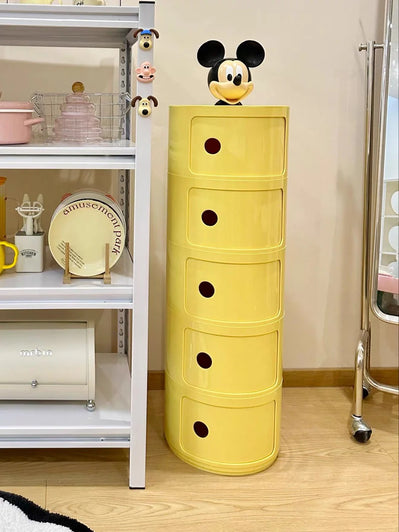 Yellow storage cabinet with black circular handles next to a white shelf unit.