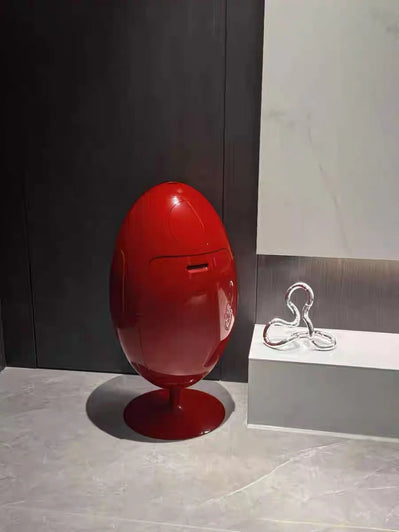 Red egg-shaped object on a gray floor with a dark wall in the background