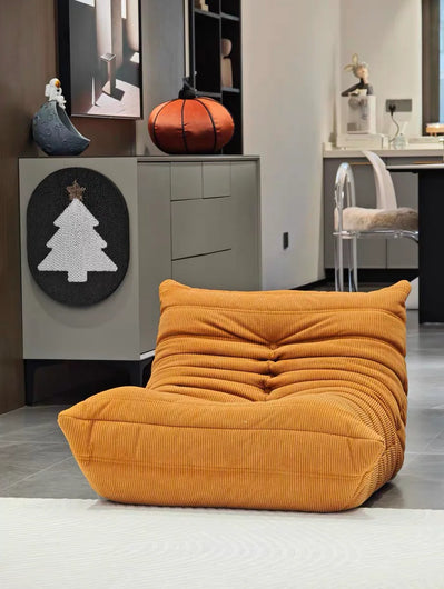 Orange bean bag chair in a modern interior setting with a cabinet and decorative items.