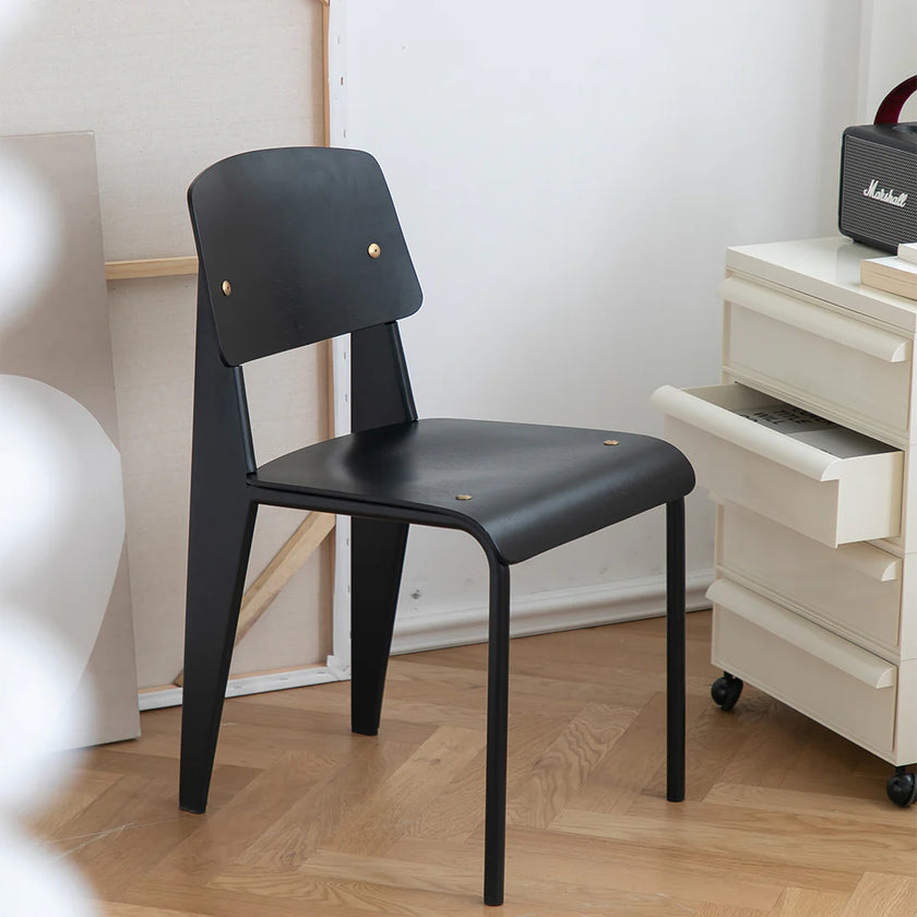 Black chair on a wooden floor with a white cabinet in the background