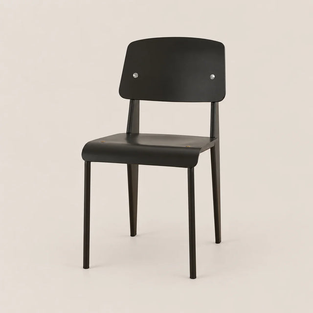 A minimalist black chair with a curved backrest and seat, featuring two small silver rivets on the backrest, set against a solid light beige background.