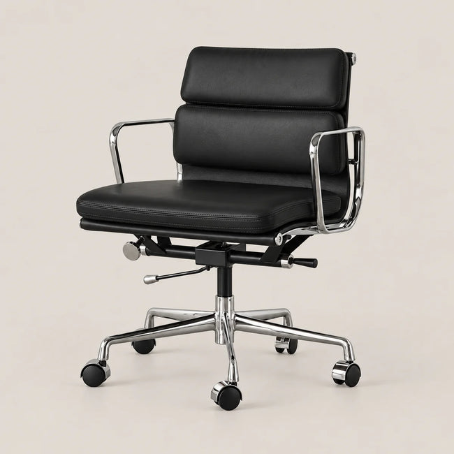 A modern black leather office chair with chrome metal armrests and a five-star wheeled base, shown on a plain beige studio background.