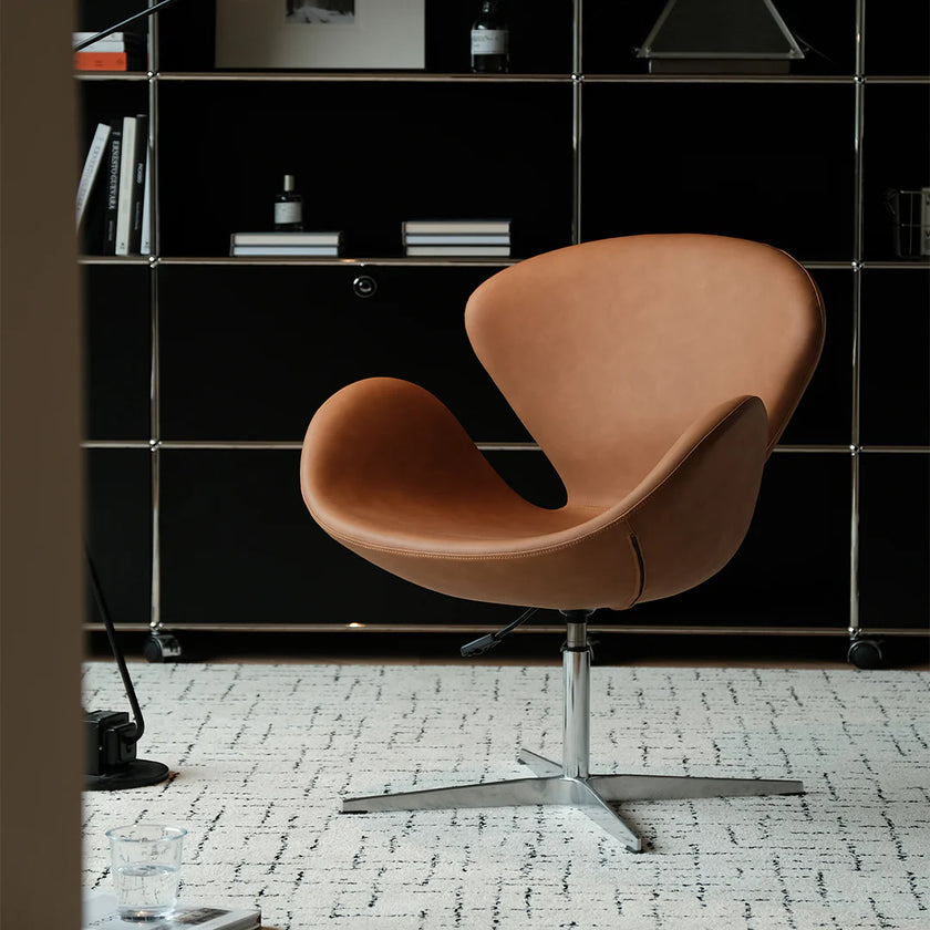 Brown chair in a room with a black bookshelf and white floor.