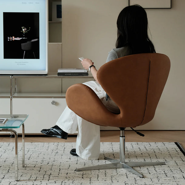 Person sitting on a brown chair in a living room, watching television.