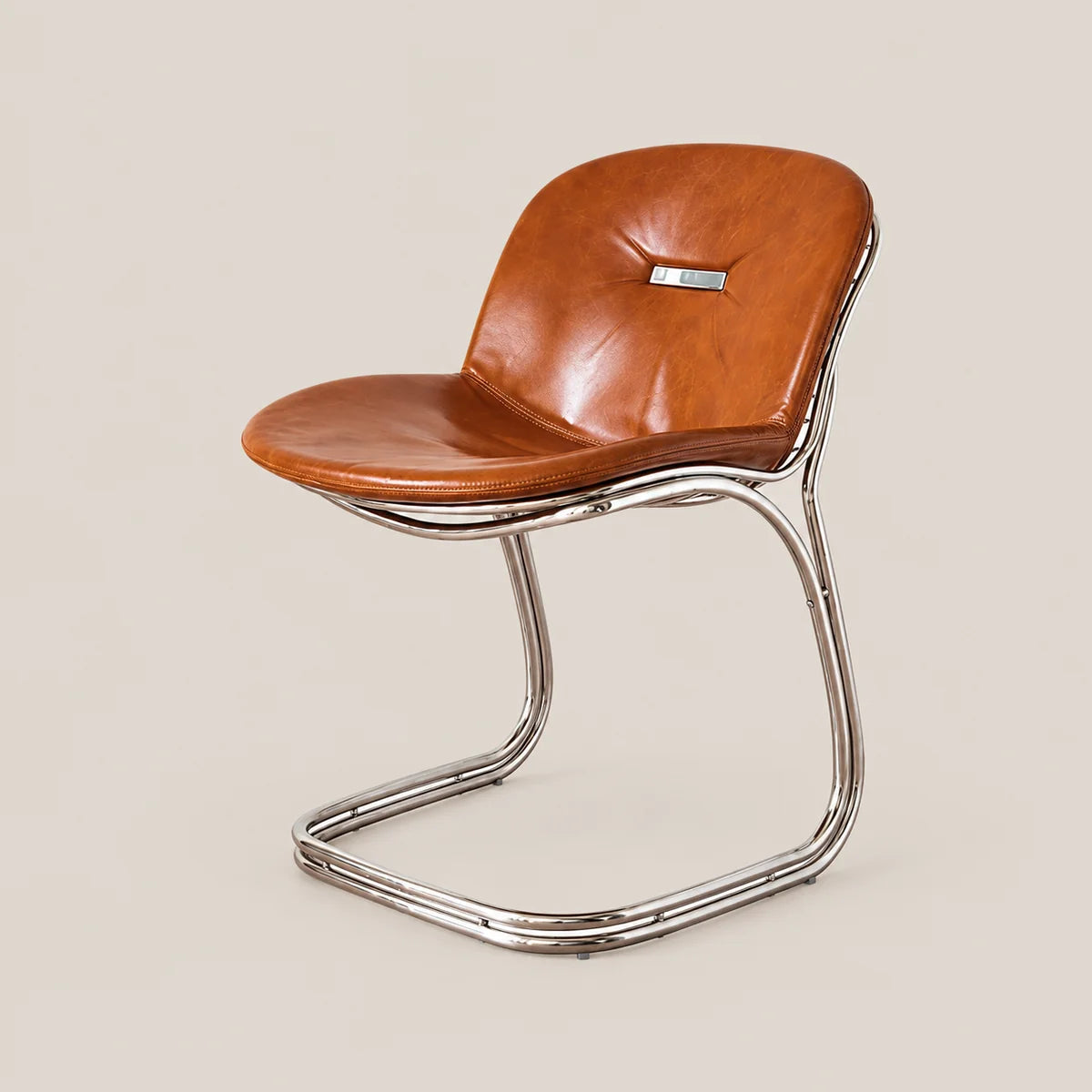 A mid-century modern side chair with a curved cognac brown leather seat and backrest, supported by a polished chrome cantilevered metal base, set against a solid light beige background.