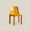 A glossy mustard yellow molded plastic chair on a light beige background.