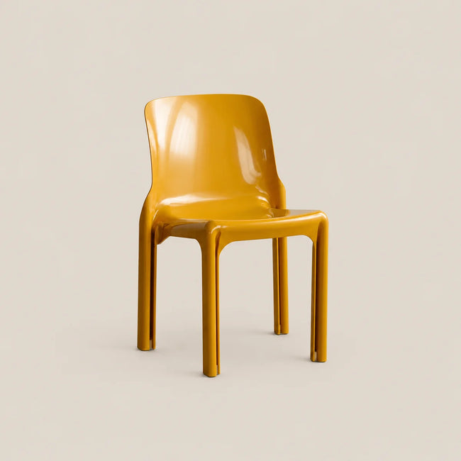 A glossy mustard yellow molded plastic chair on a light beige background.