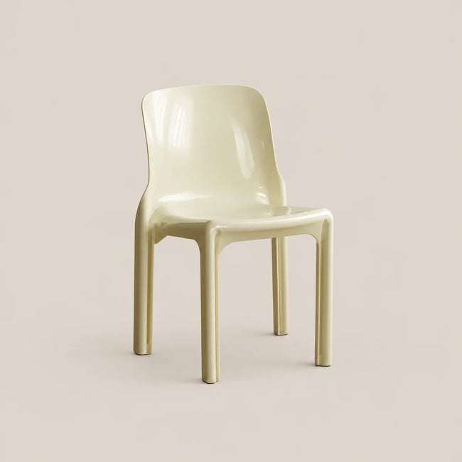 A glossy molded plastic dining chair in a pale cream or light beige color, shown from a three-quarter angle against a solid, warm beige background.
