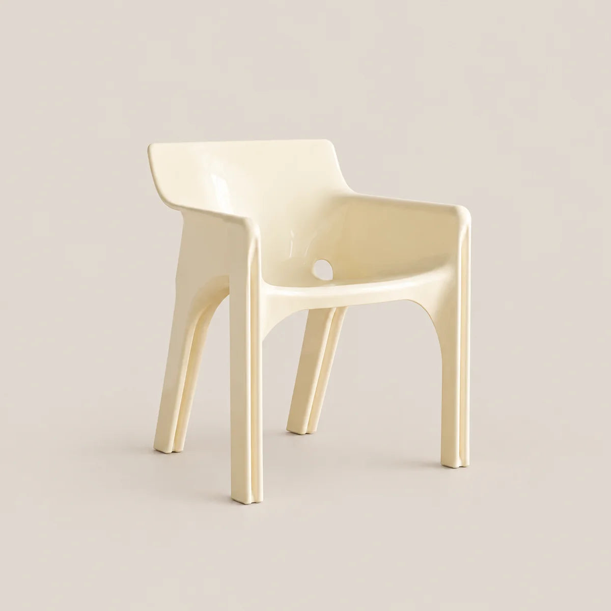 A modern molded plastic armchair in a glossy cream color, set against a solid, warm off-white background.