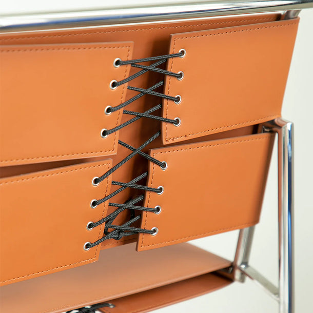 Close-up of a brown leather bag with black laces on a white background