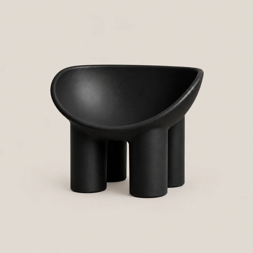 A minimalist black molded stool with a rounded, bowl-like seat and four cylindrical legs, shown against a solid light beige background.