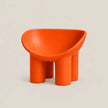 A bright orange molded plastic children's stool with a rounded, bowl-like seat and four cylindrical legs, shown on a neutral light beige background.