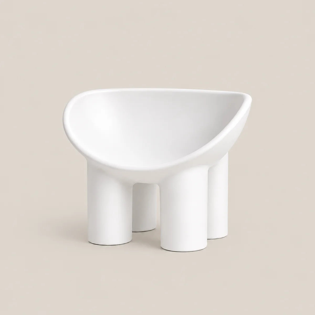 A minimalist white molded chair with a wide, rounded seat and four cylindrical legs, shown against a solid beige background.