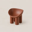 A small terracotta-colored molded stool with a rounded, bowl-like seat and four cylindrical legs, shown on a plain warm beige background.