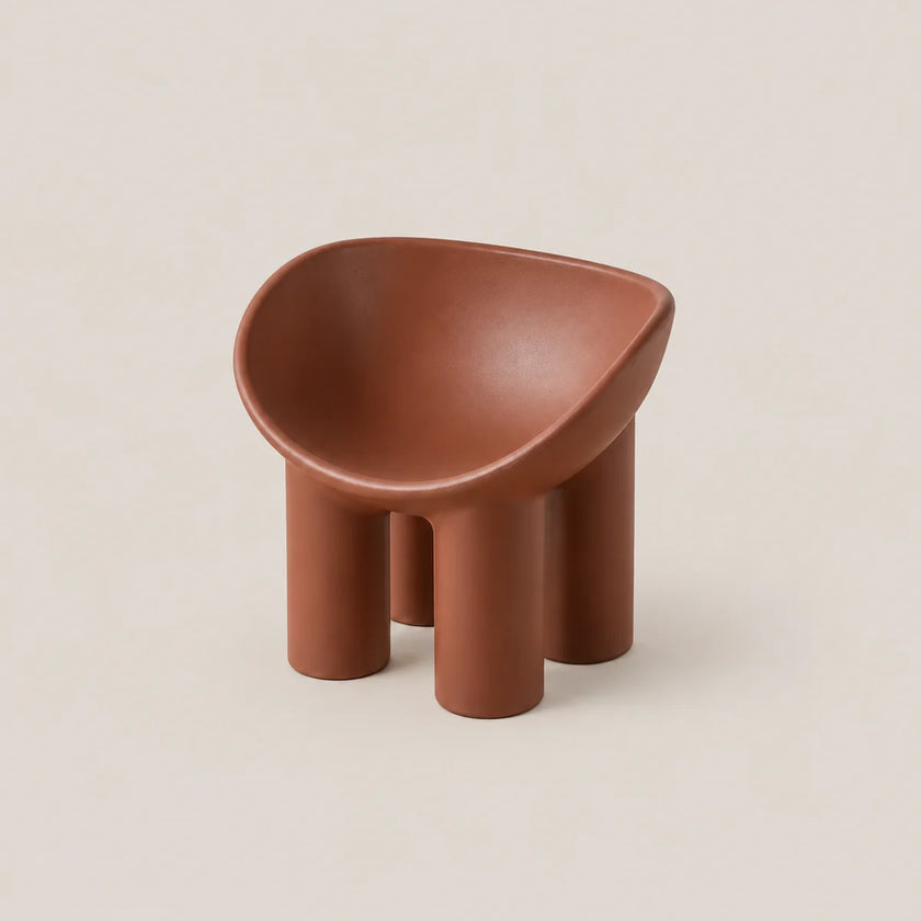 A small terracotta-colored molded stool with a rounded, bowl-like seat and four cylindrical legs, shown on a plain warm beige background.