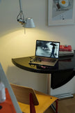 Small desk with laptop, books, and lamp in a room setting