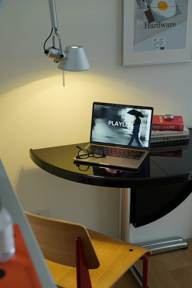 Small desk with laptop, books, and lamp in a room setting