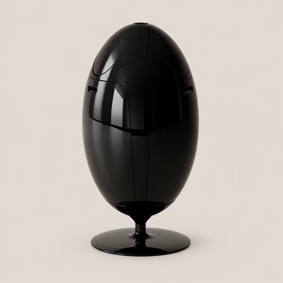A glossy black egg-shaped decorative object with a pedestal base, photographed against a plain warm light beige background.