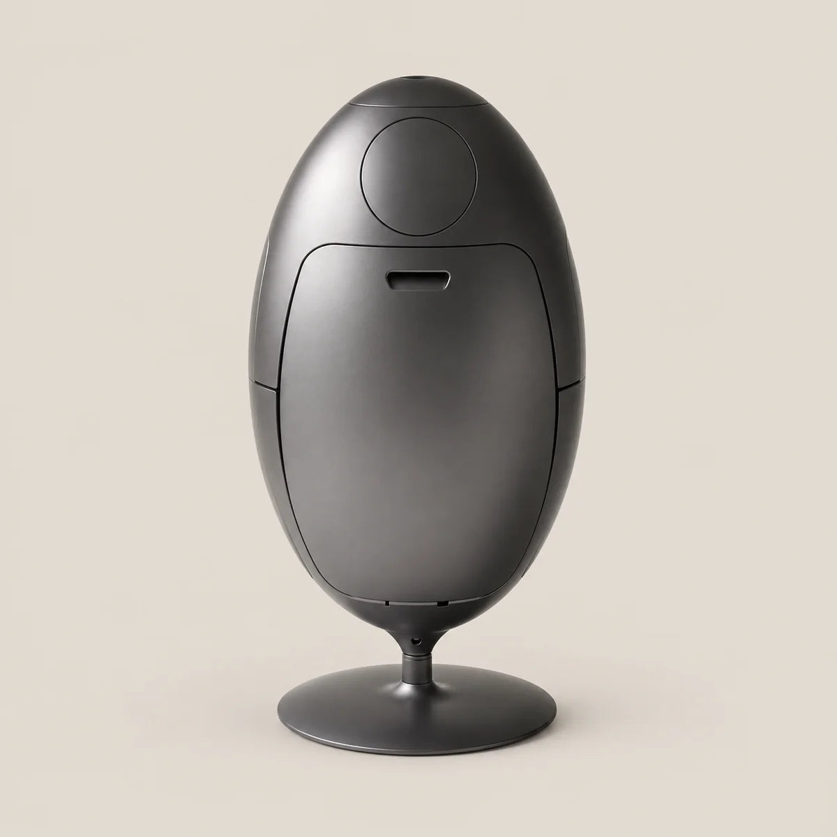 A matte black egg-shaped electronic device on a matching circular stand, photographed against a solid light beige background.