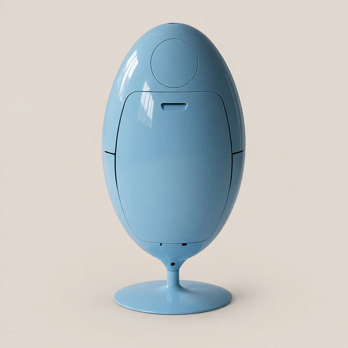 A glossy light blue egg-shaped electronic device on a matching round pedestal base, photographed against a solid warm beige background.