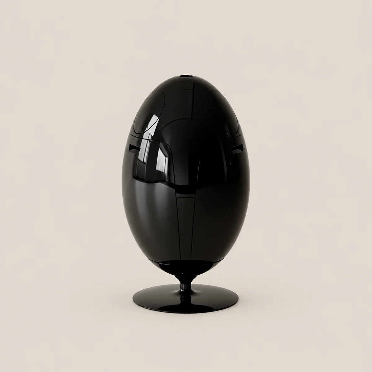 A glossy black egg-shaped sculpture or decorative object on a matching round base, photographed against a plain warm light beige studio background.