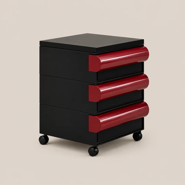 A modern three-drawer rolling storage cabinet with a glossy black body and contrasting deep red curved drawer pulls, shown on a light beige background.
