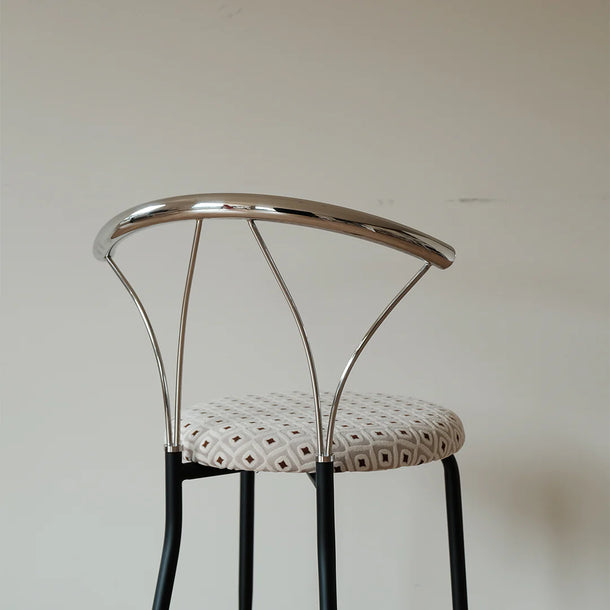 Modern bar stool with metal backrest and patterned seat on a plain background
