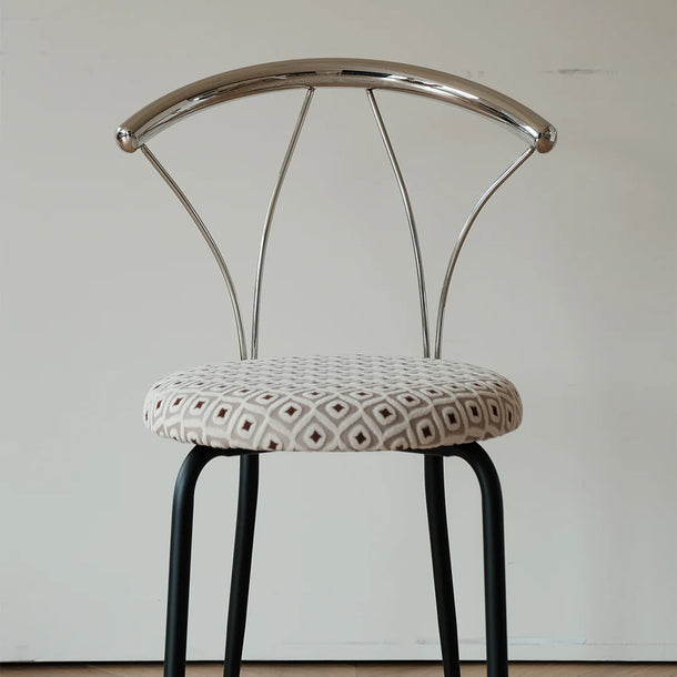 Chair with metal backrest and patterned cushion on a plain background