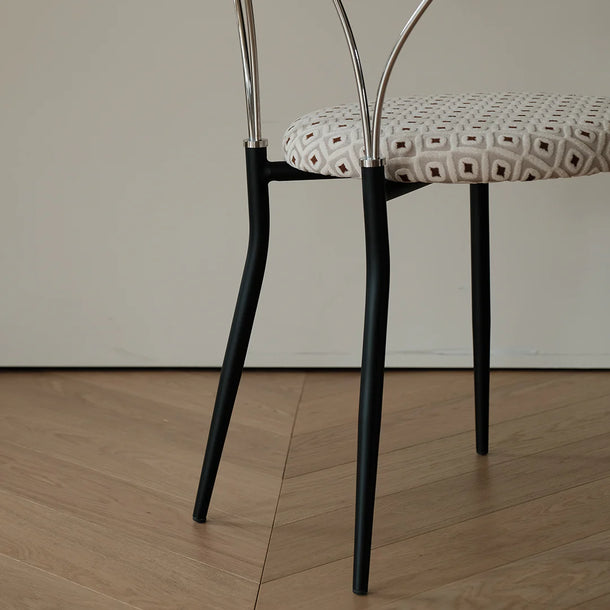 Chair with black legs and patterned seat on a wooden floor.