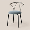 A modern dining chair with a textured light blue boucle upholstered seat, black metal legs, and a curved chrome wire backrest, set against a solid beige background.