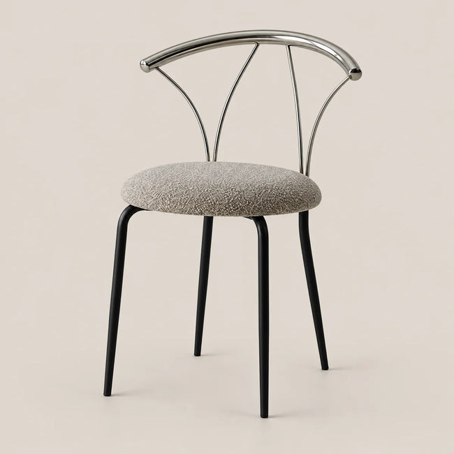 A modern dining chair with a round textured gray upholstered seat, black tapered legs, and a curved polished metal backrest, shown against a solid light beige background.
