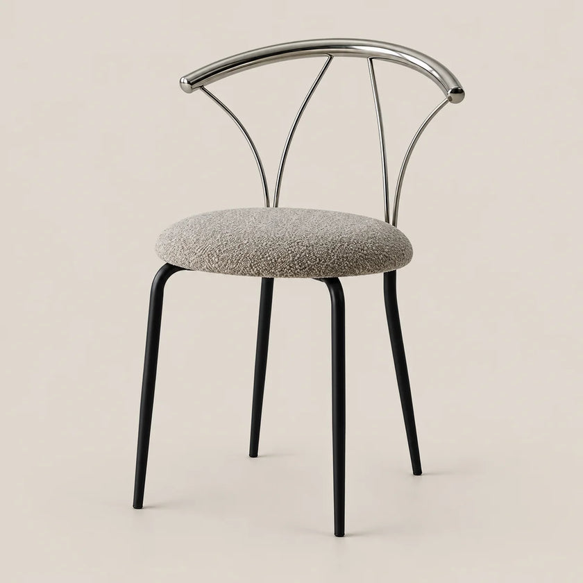 A modern dining chair with a round textured gray upholstered seat, black tapered legs, and a curved polished metal backrest, shown against a solid light beige background.
